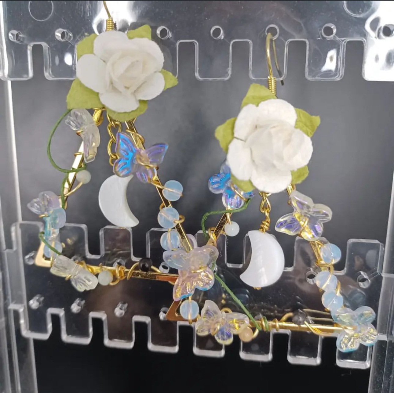 Wooden shelf with gray and olive drab green baseball caps, next to wooden clothes hanger with sweaters.